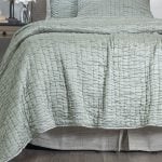 Amity home hadon quilt in seaglass with a luxurious puckered grid texture draped over a bed