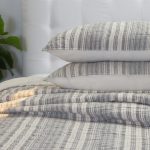 Amity home aiden quilt and matching shams in a grey and off white striped pattern with soft quilted texture styled on a bed