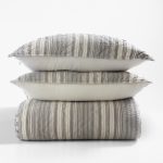 Amity home aiden quilt and two matching pillows stacked in grey and cream vertical stripes with a soft quilted texture