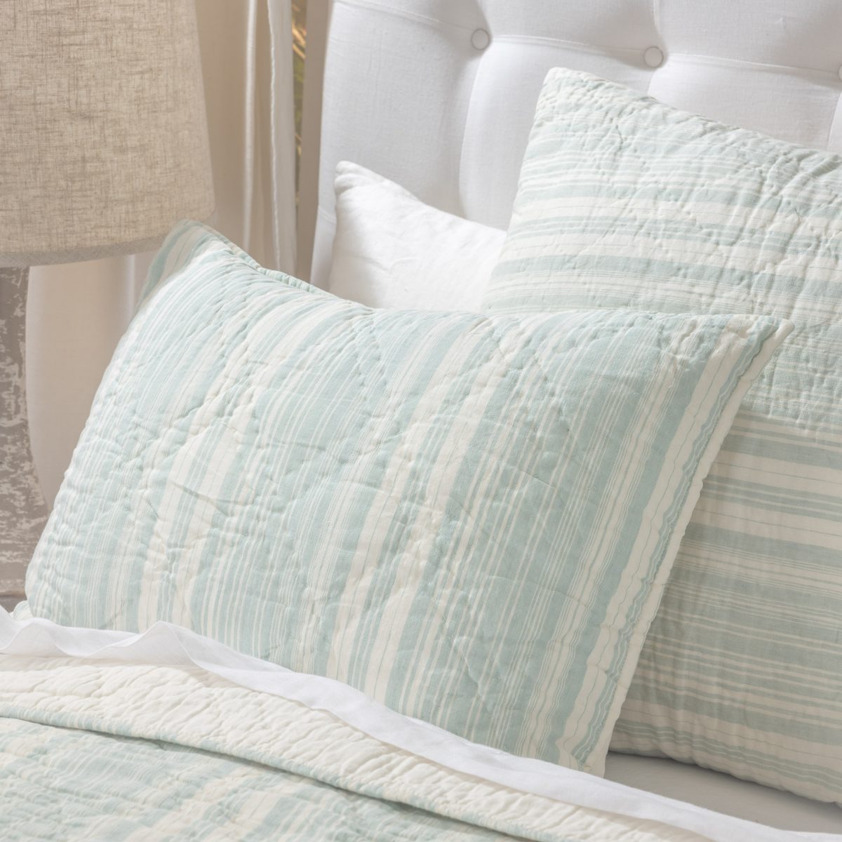 Amity home aiden quilt in seaglass and cream stripes with a soft quilted texture styled on a bed