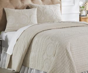 Amity home maya quilt   light beige quilt with intricate white embroidered floral and circular patterns styled on a luxury bed