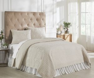Amity home maya quilt in natural beige with intricate circular embroidered patterns and subtle linear quilting styled on a bed