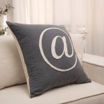 Amity home at pillow in charcoal grey   appliqued  symbol with frayed edge