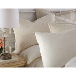 Amity home simona rayon velvet quilt   ivory velvet with diamond quilting styled as a pillow on a luxurious bed